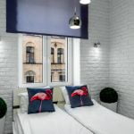 Malutka sypialnia z białą cegłą na ścianach oświetloną lampkami led