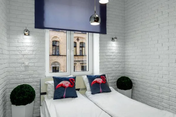 Malutka sypialnia z białą cegłą na ścianach oświetloną lampkami led